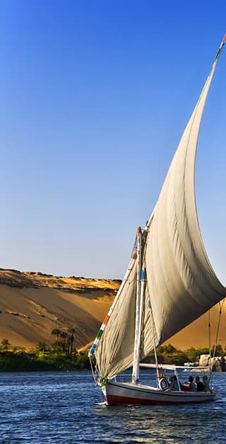 Voilier sur le Nil avec une dune de sable en arrière-plan